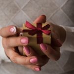 Woman,Hands,Holding,A,Small,Present,Box,With,Red,Ribbon